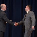 Doctor Potteiger shaking hands with an award recipient in a grey suit and black tie